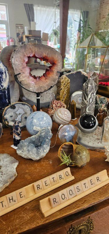 Crystal shop display with geodes and polished stones on a wooden sign reading “THE REEL ROCKSTER”