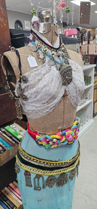 Mannequin wearing a sequined silver top, beaded necklace, and turquoise skirt in a shop display
