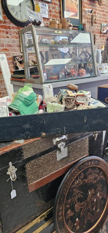 Vintage display case with assorted small antiques and trinkets in front of a brick wall.
