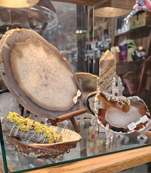 Small decorative boat-shaped art pieces displayed on a glass shelf in a shop window