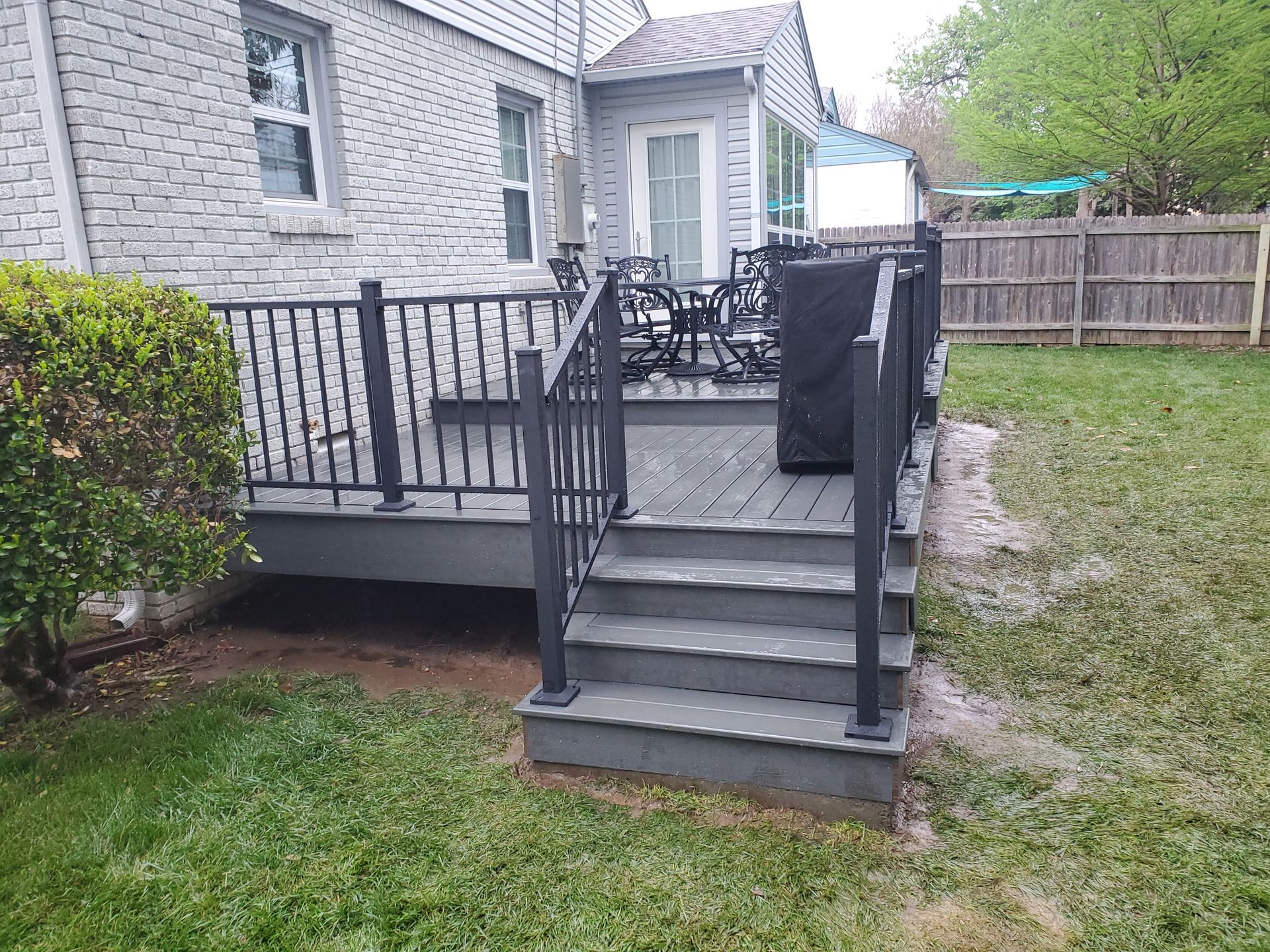 A deck with stairs and a grill in the backyard of a house.