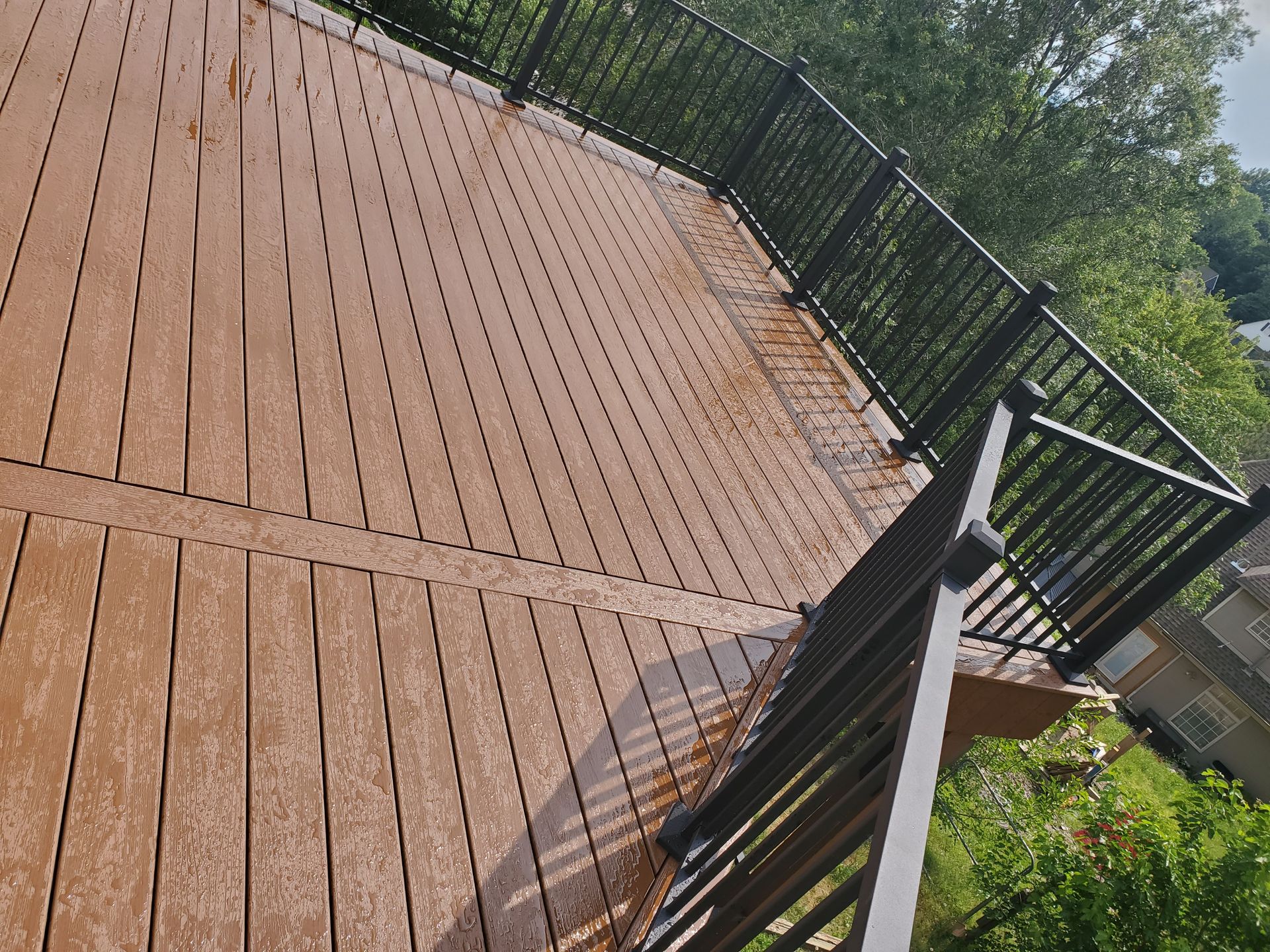 A wooden deck with a metal railing and trees in the background