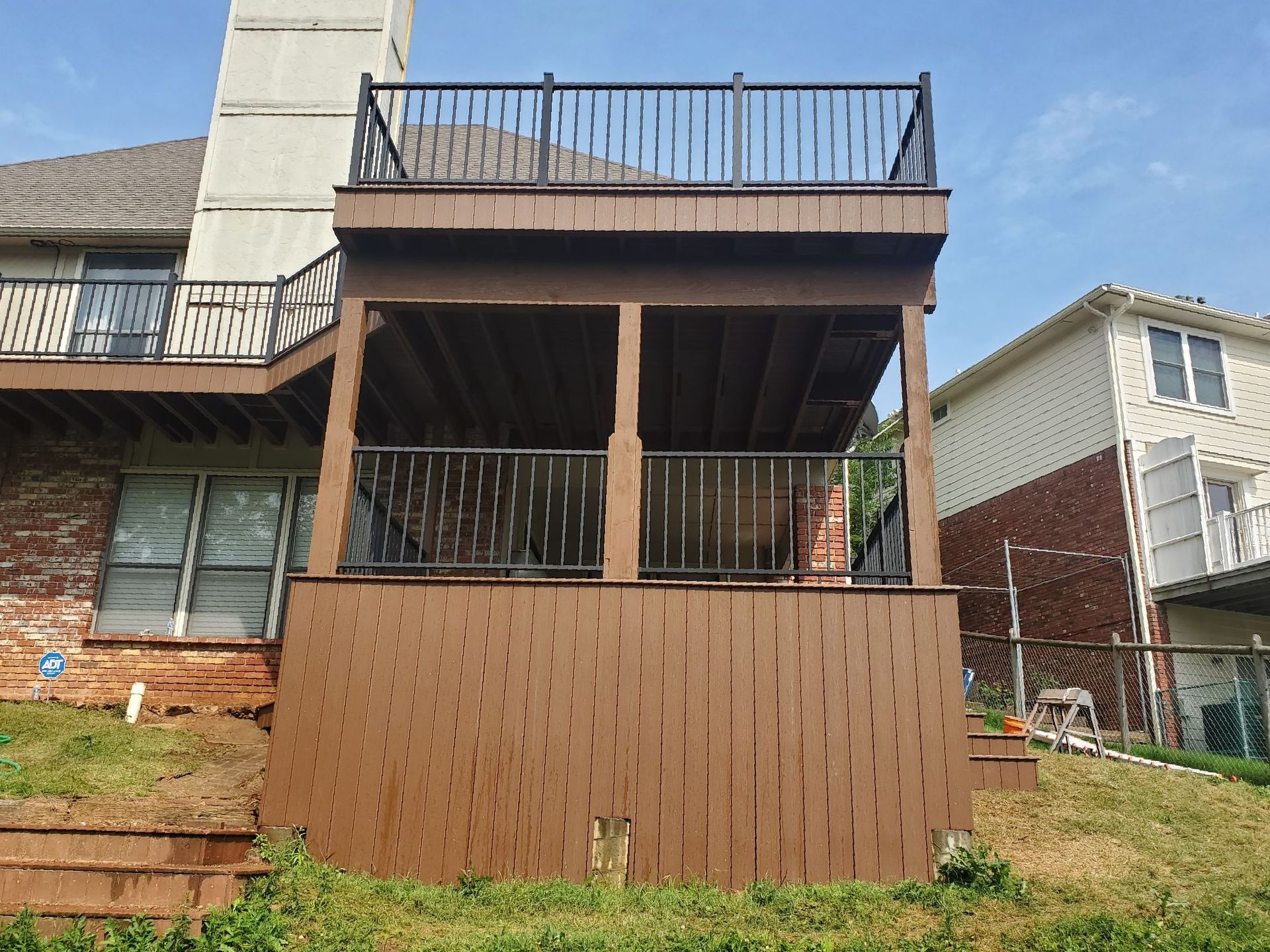 The back of a house with a large deck and stairs leading up to it.