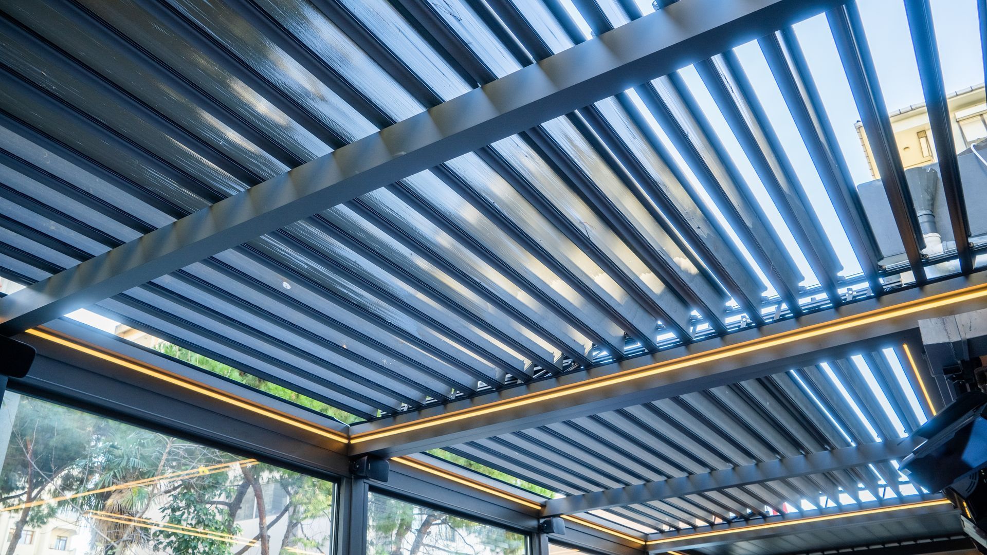 Covered patio ceiling with blue slatted beams and strip lights, viewed from below