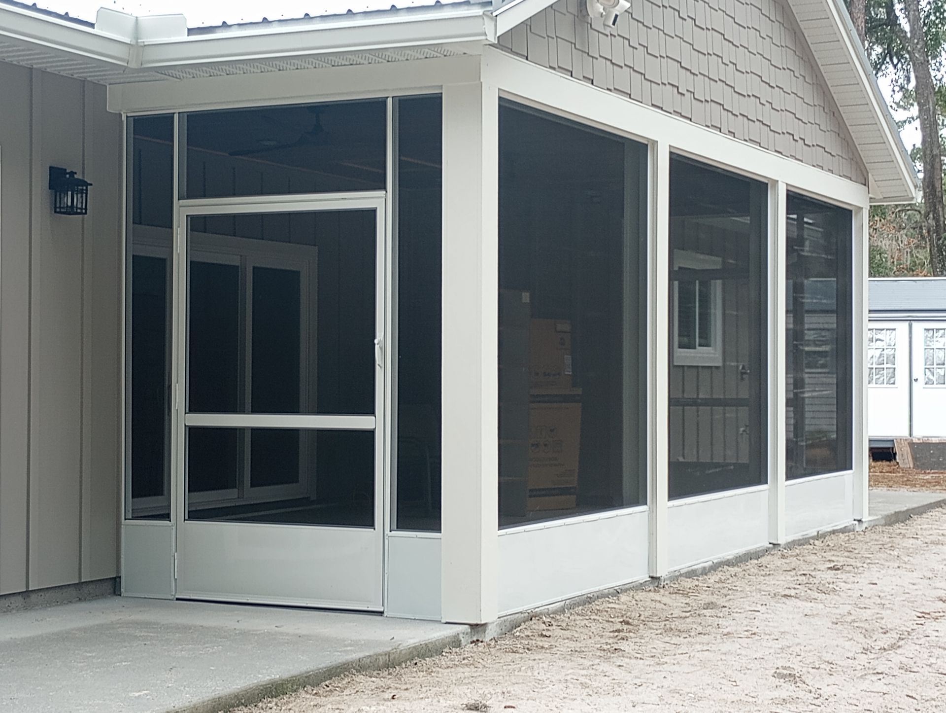 Screened porch on a light-colored house with white trim and dark window panels