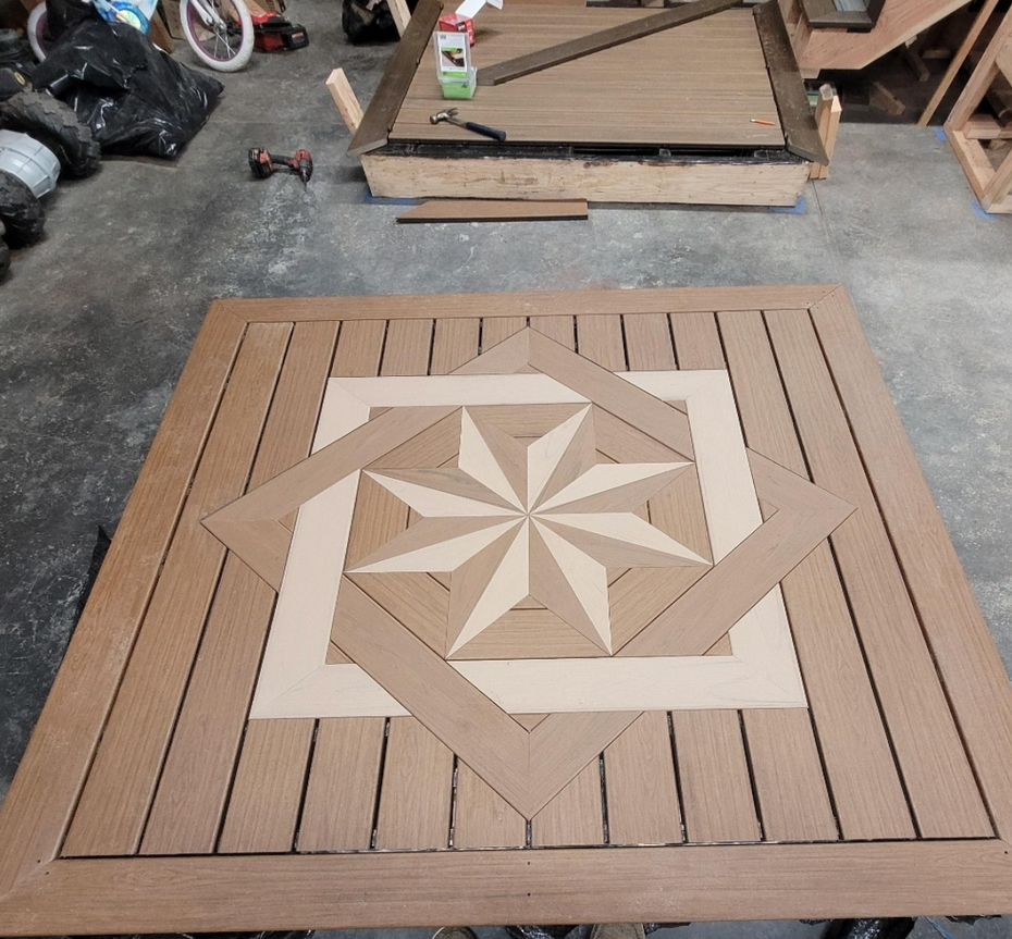 Geometric wooden tabletop with tan and cream starburst inlay, shown in a workshop setting