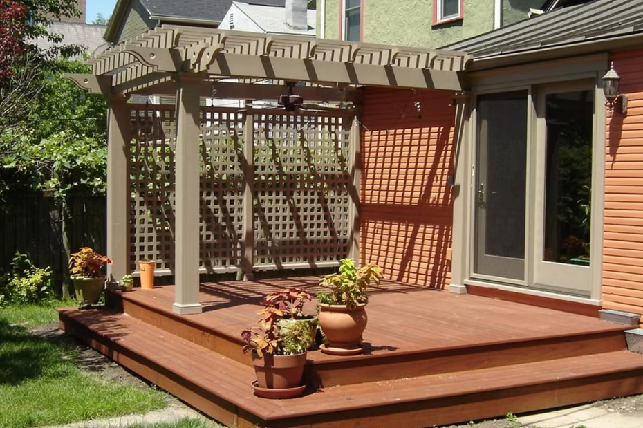 Backyard wooden deck with pergola, potted flowers, and sliding glass doors on a house