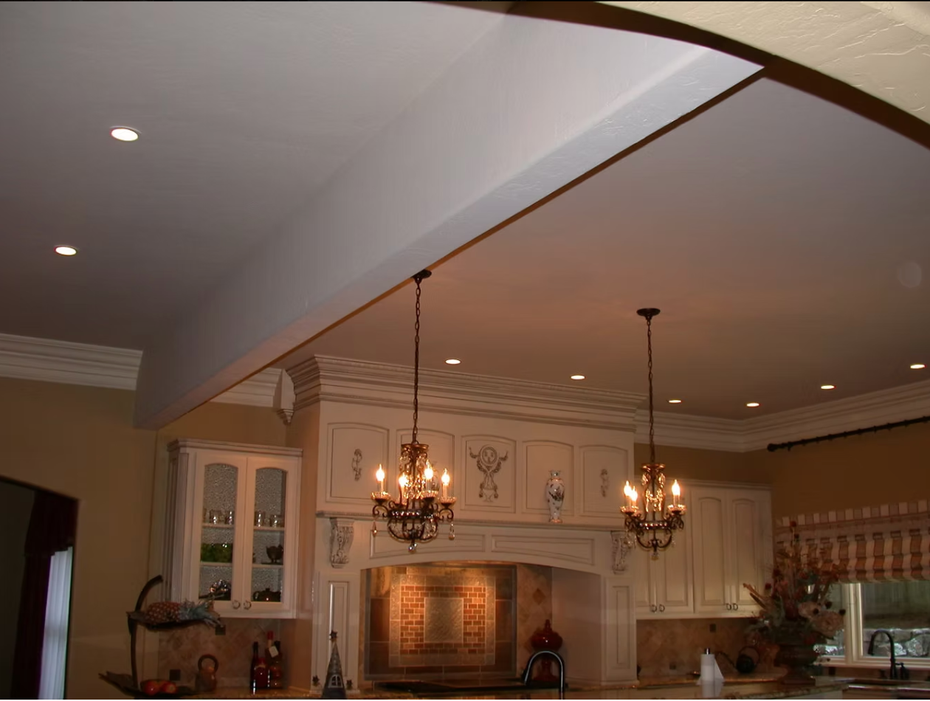 Warm kitchen with cream cabinets, island, hanging chandeliers, and recessed ceiling lights