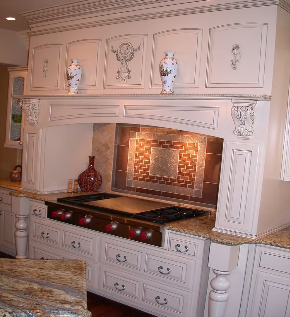 White ornate kitchen with a lit brick stove alcove, decorative moldings, and countertop vases