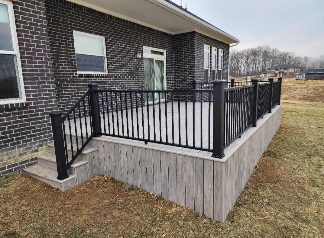 A brick house with a deck and stairs in front of it.