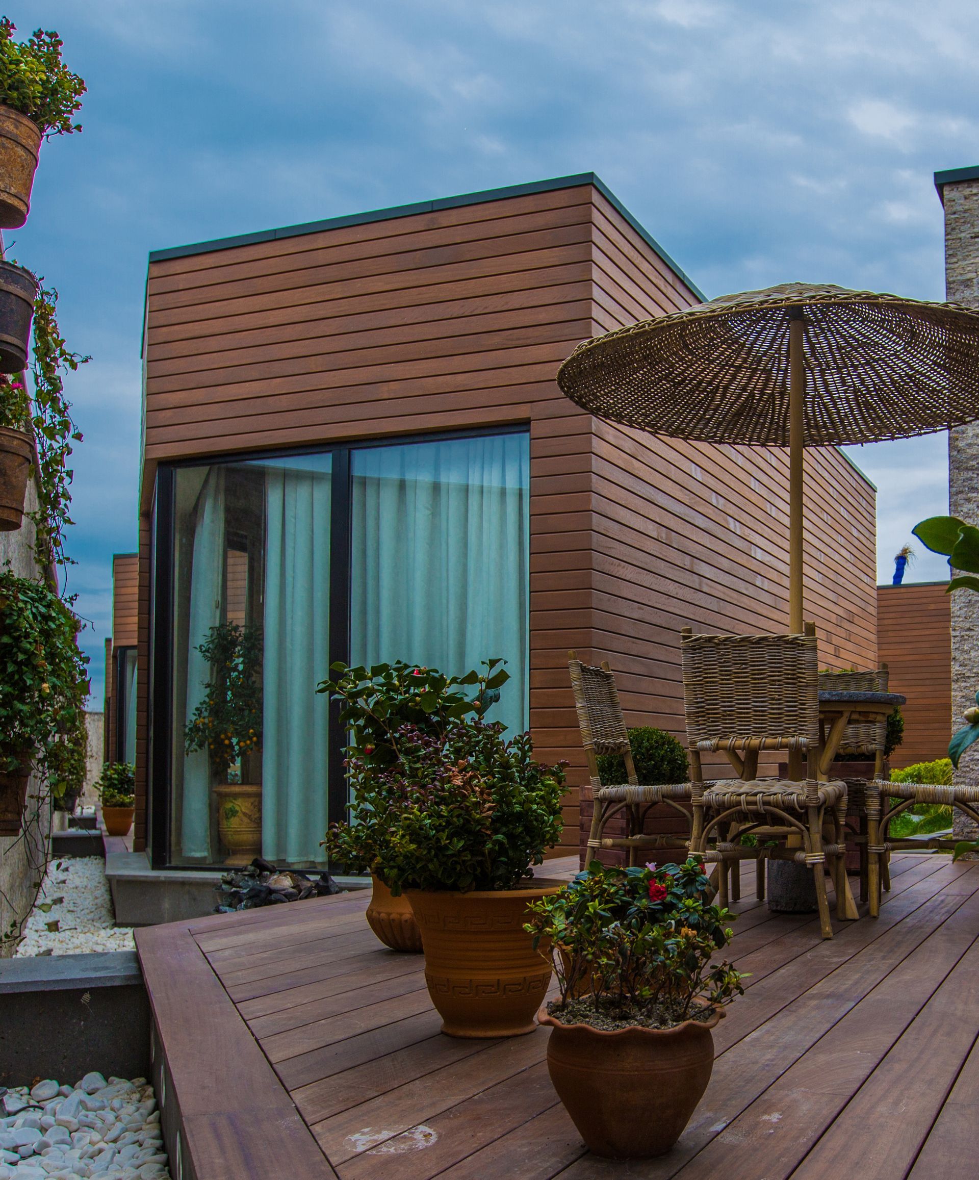 A wooden deck with potted plants and a wicker umbrella