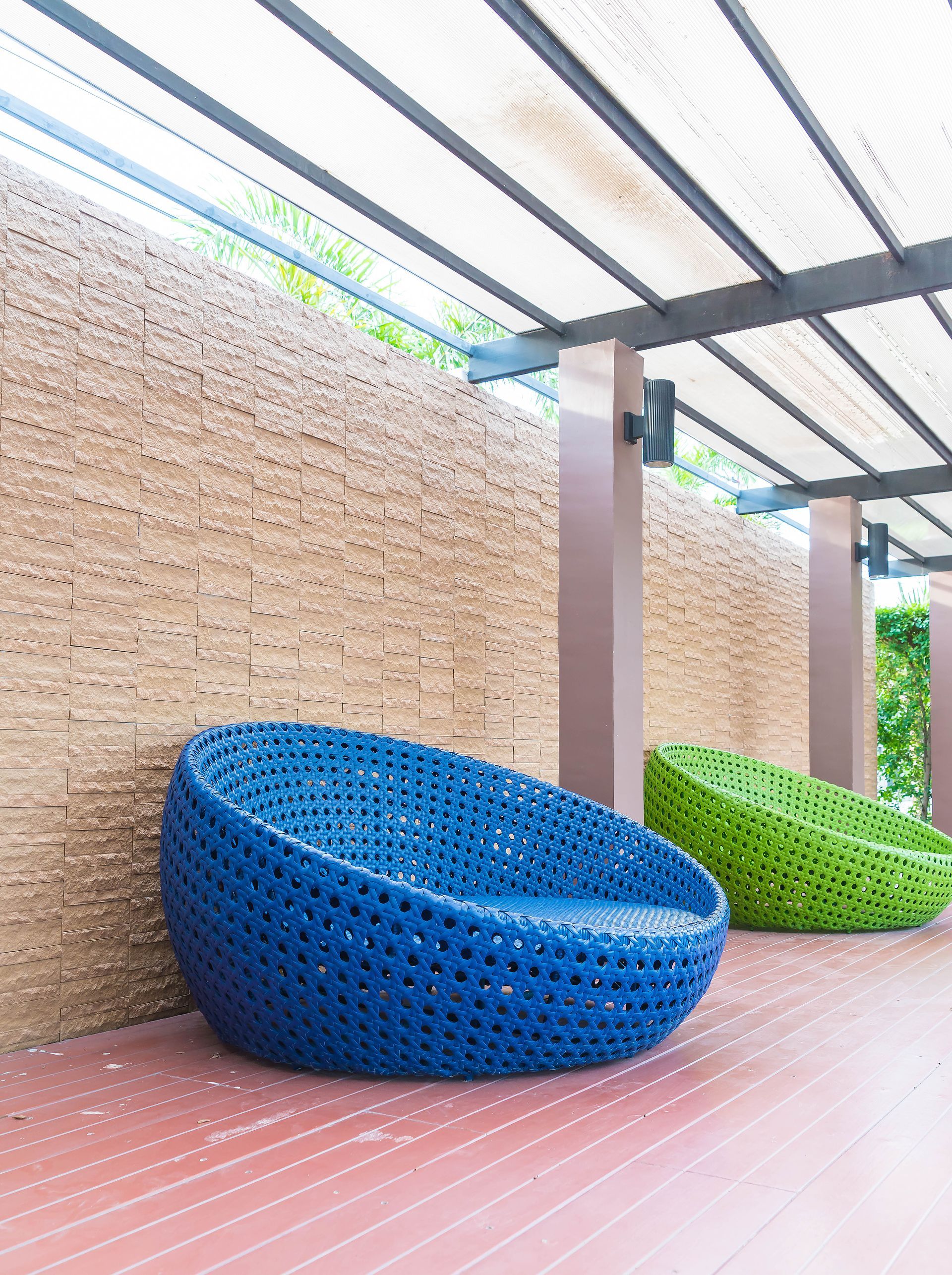A blue chair and a green chair are sitting next to each other on a wooden deck.