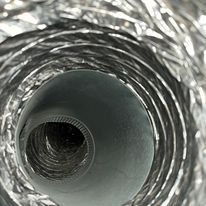 Gros plan sur l'intérieur d'un conduit ou d'un tube de ventilation métallique flexible argenté.