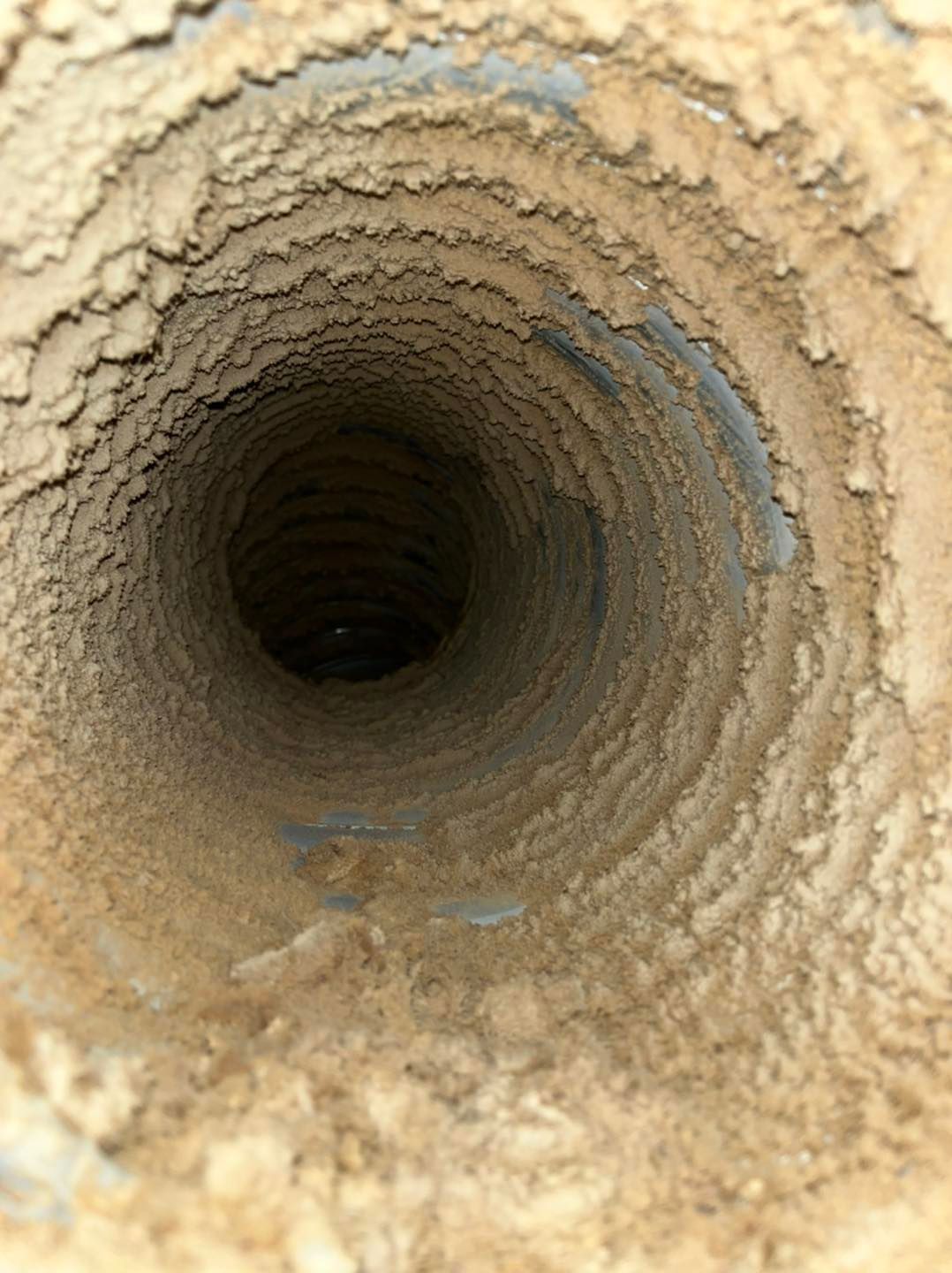 Gros plan sur l'intérieur rugueux d'un tunnel ou d'un tuyau beige avec une ouverture circulaire sombre au centre