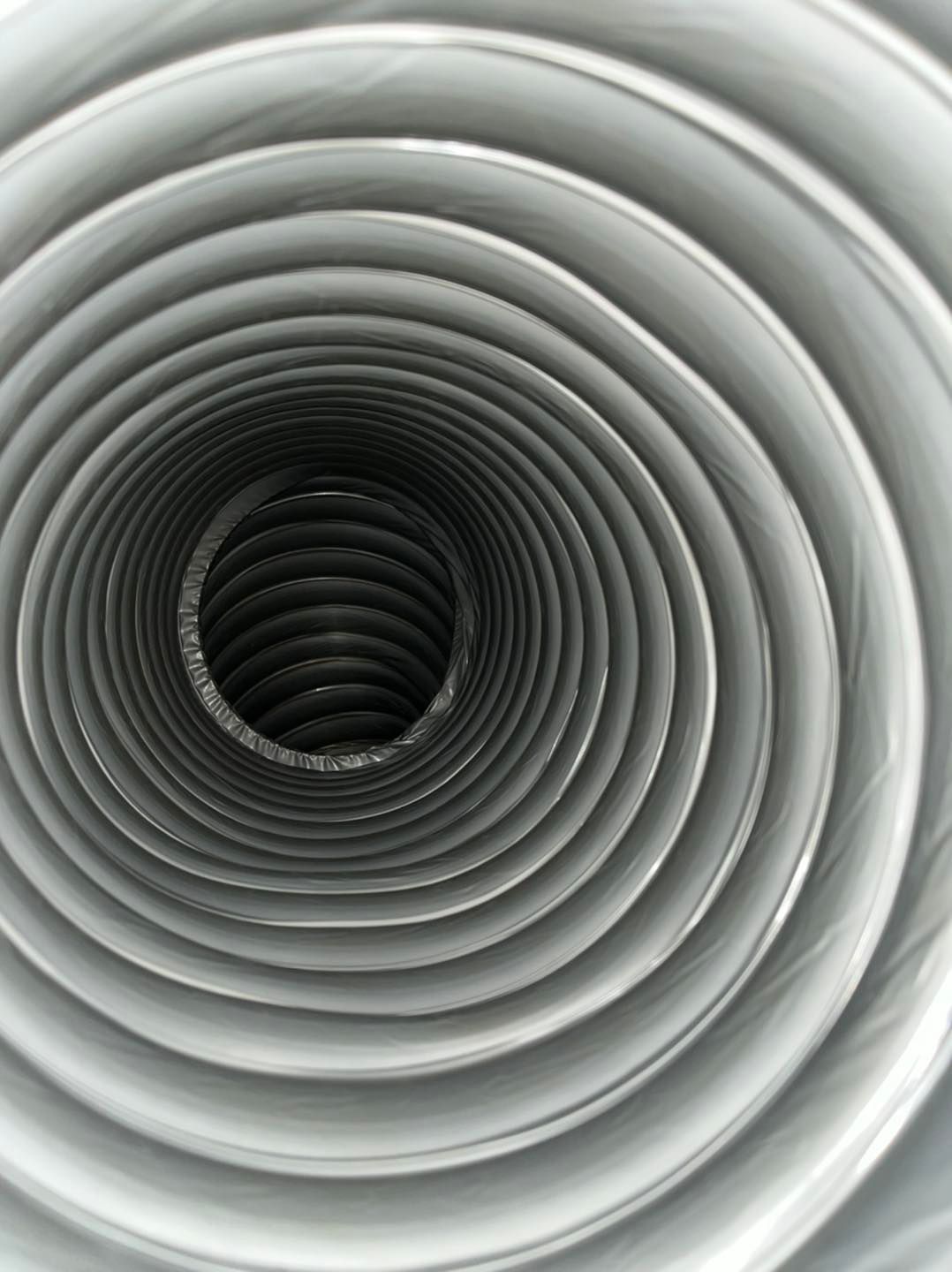 Gros plan sur un tube flexible gris enroulé en spirale.