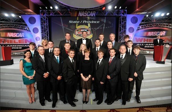 A group of people standing in front of a nascar sign