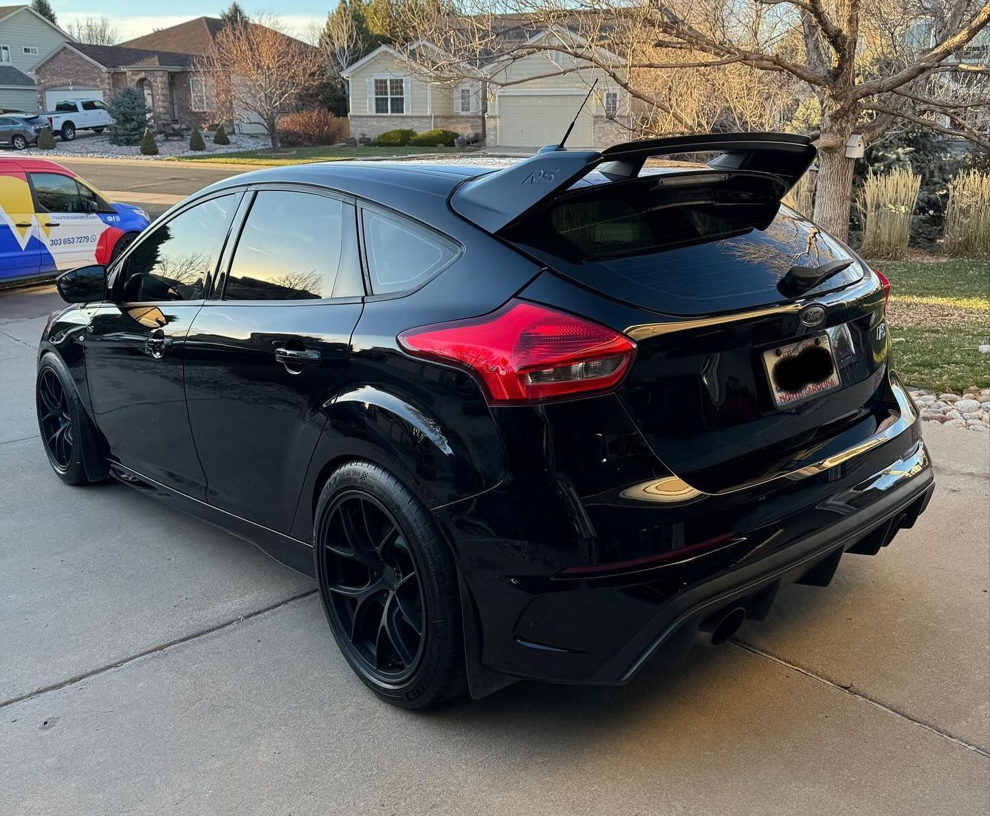 Black Ford Focus RS with a rear spoiler, parked on a driveway.