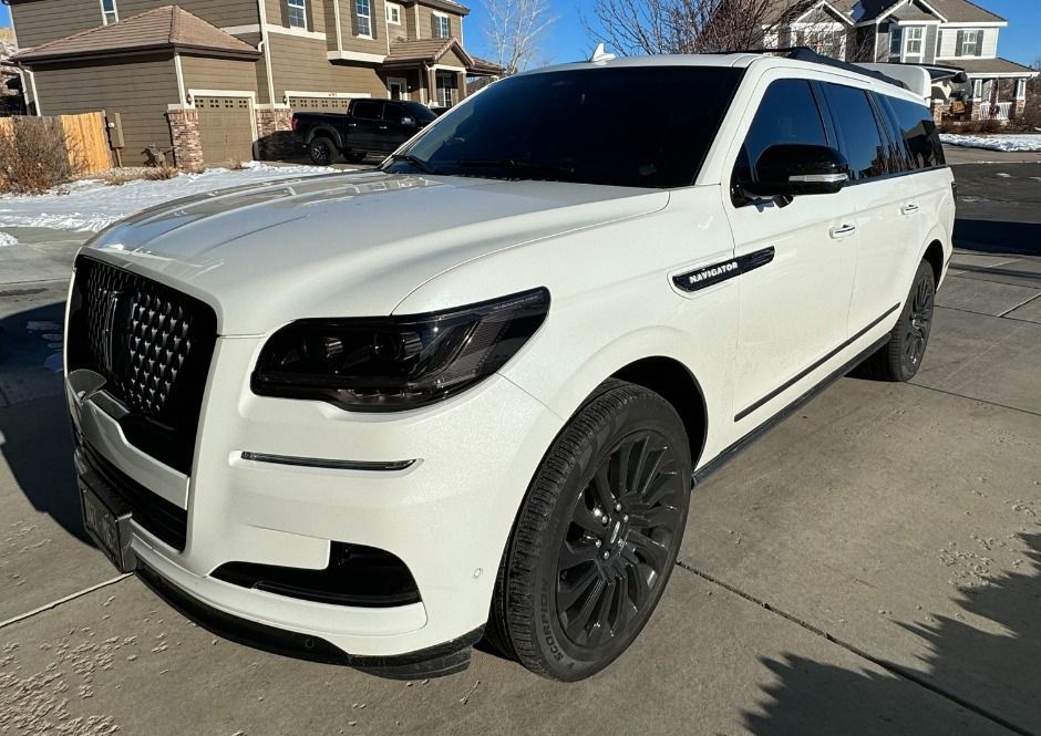 A white lincoln navigator is parked in a driveway in front of a house.