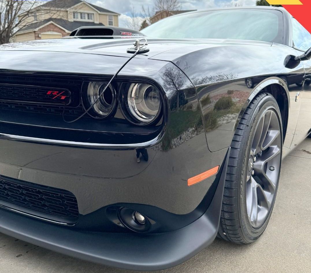 A black dodge challenger is parked on the side of the road