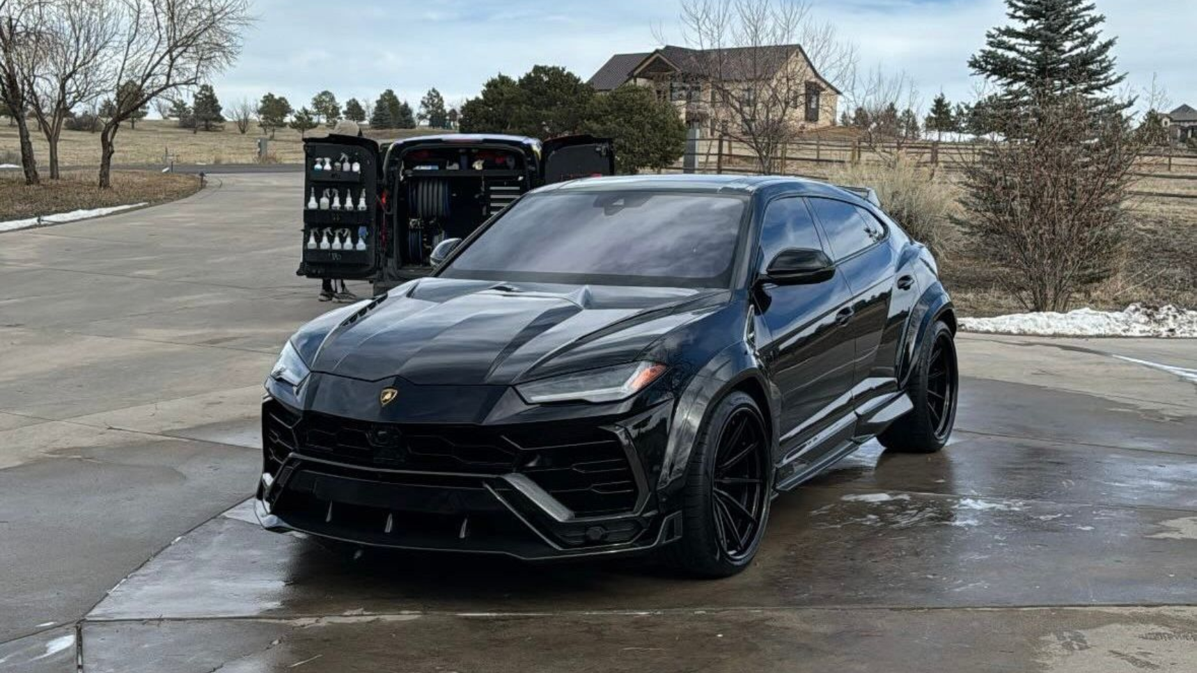 Dark gray Porsche Panamera parked on a driveway with a snowy background.