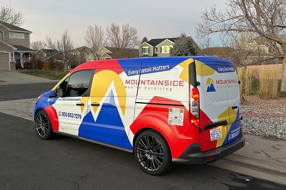 A colorful van is parked in front of a house.
