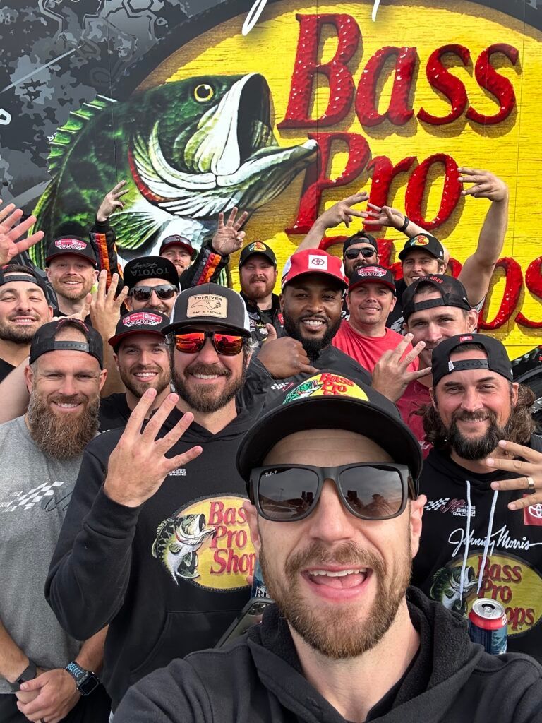 A group of men are posing for a picture in front of a bass pro shop sign.