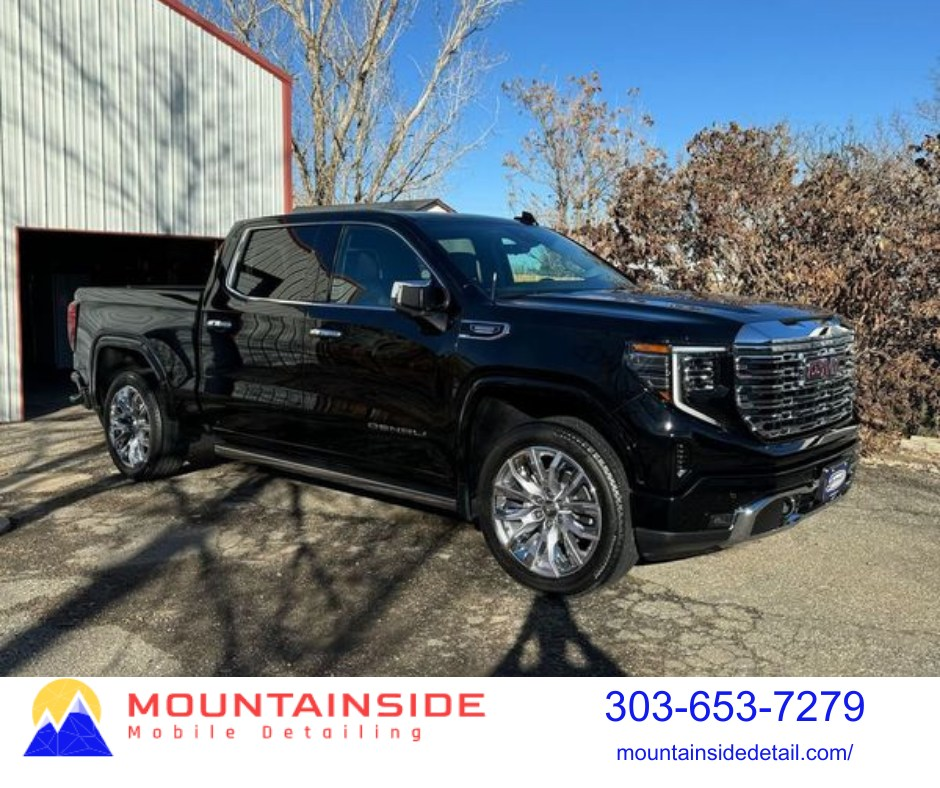 Black GMC Sierra Denali truck parked outside a building on a sunny day.
