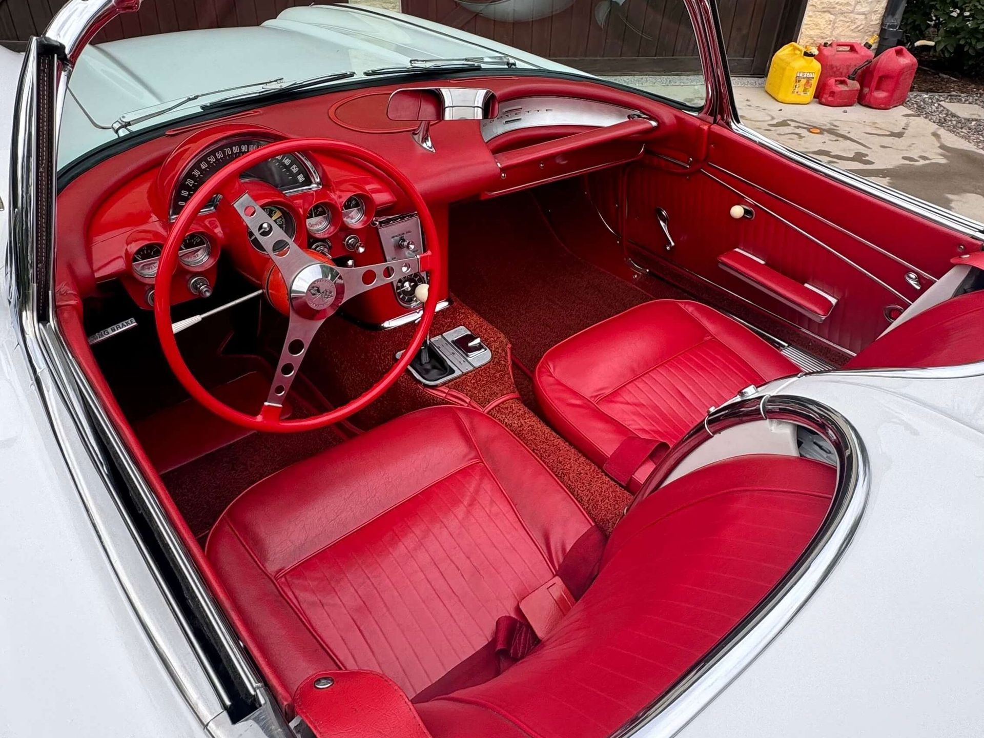 White classic convertible car interior with red seats and dashboard.