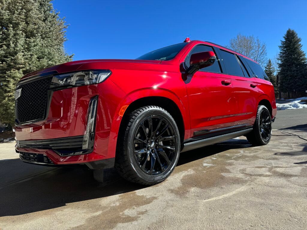 A red cadillac escalade is parked in a driveway.