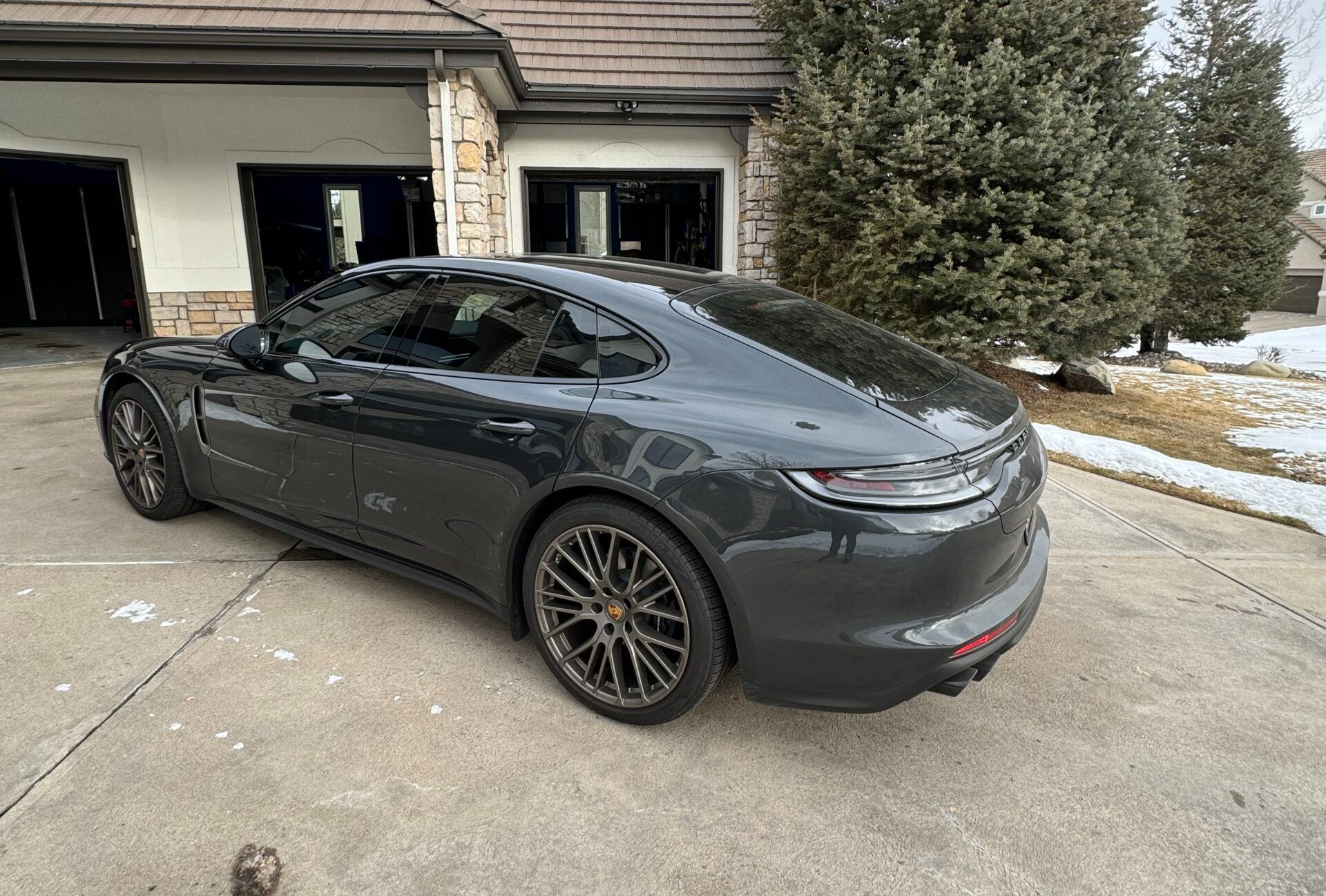 A black porsche panamera is parked in front of a house.