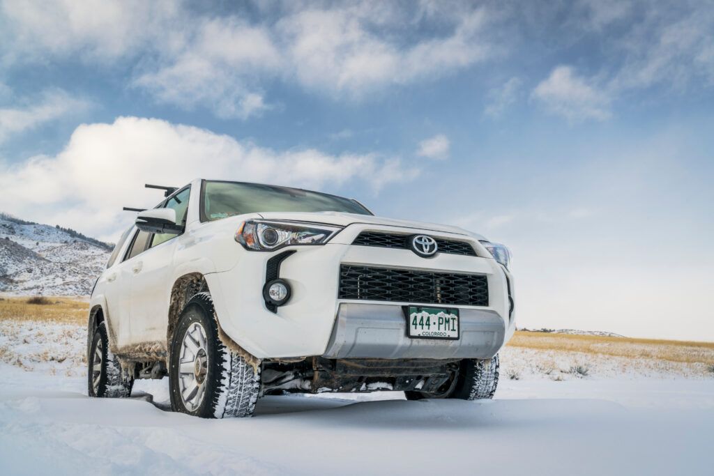 A white toyota 4runner is parked in the snow.