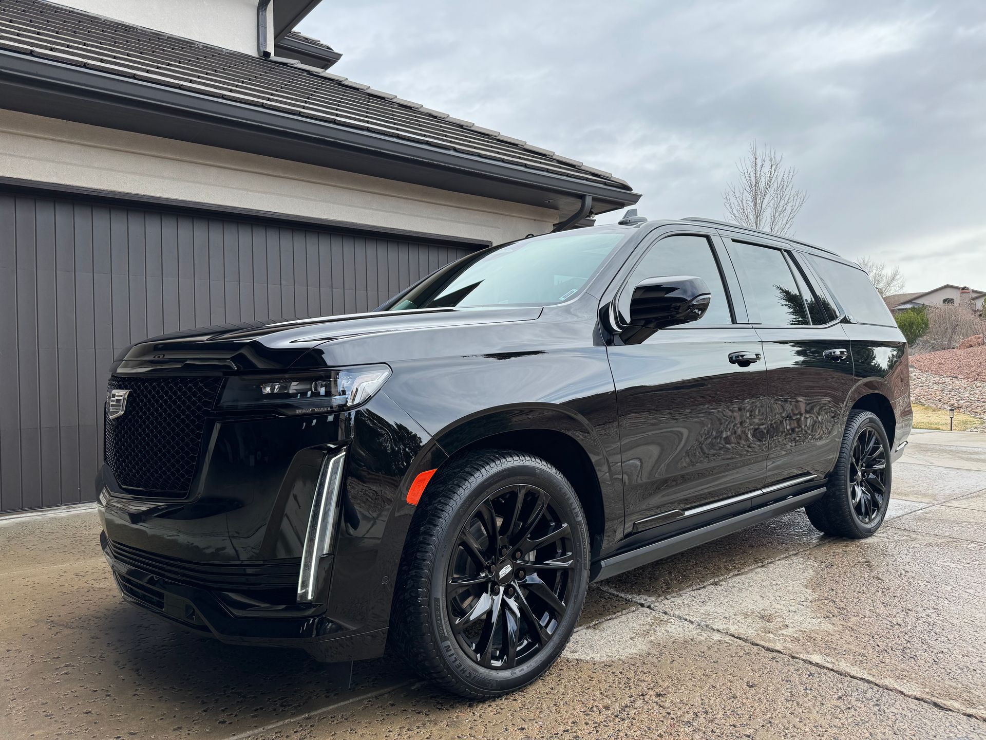 A black cadillac escalade is parked in front of a garage.