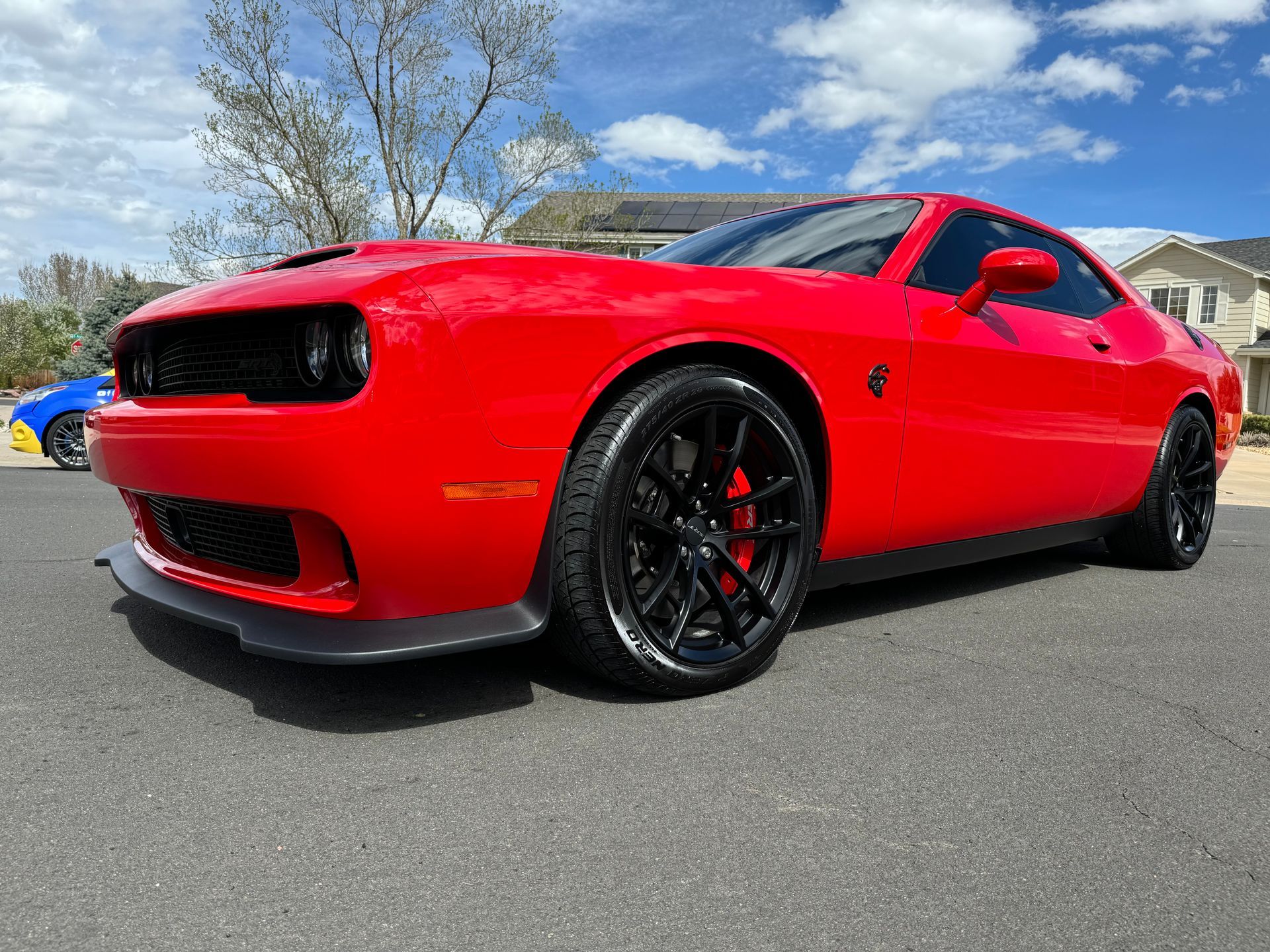 A red dodge challenger is parked on the side of the road.