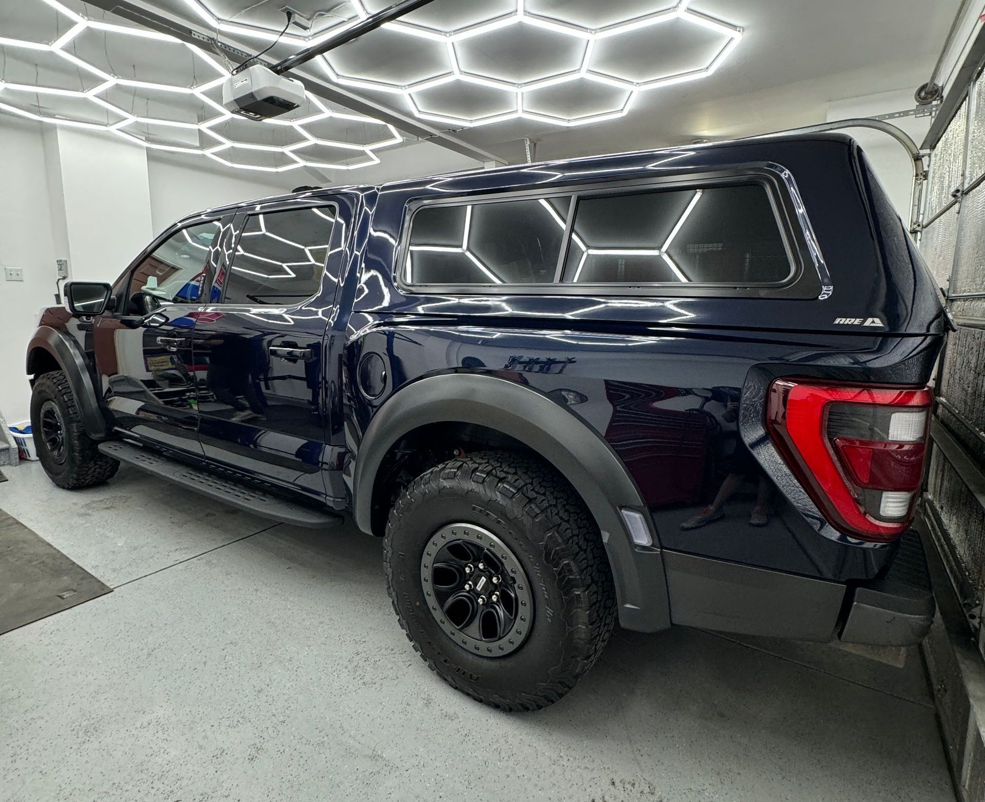 A blue truck with a canopy is parked in a garage.