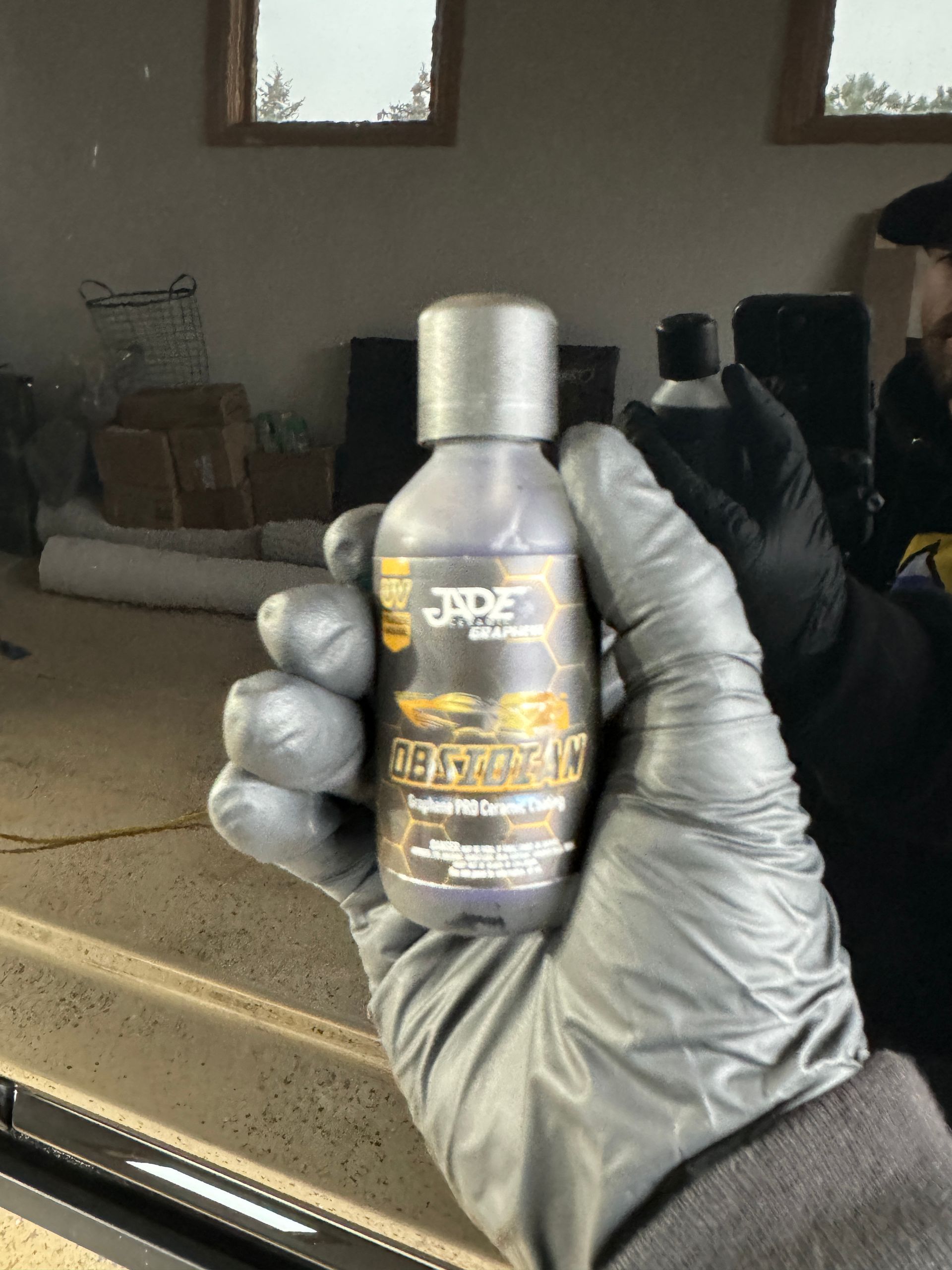 A person wearing black gloves is holding a bottle of jade