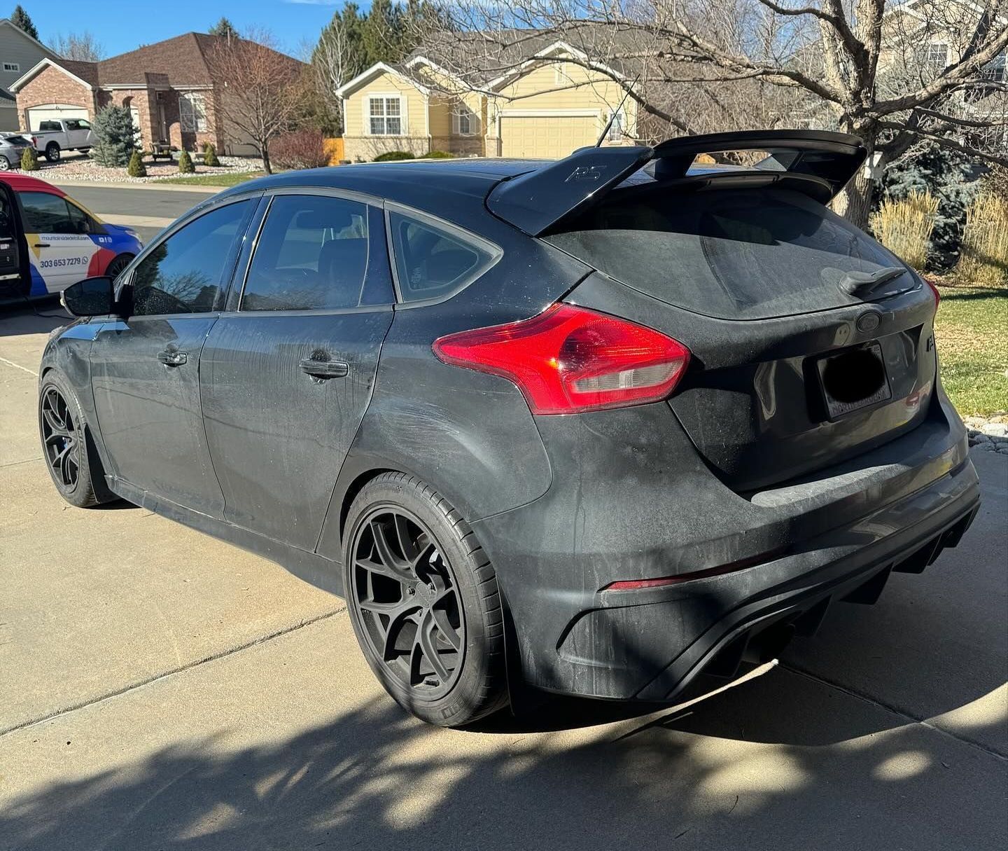 Dark grey Ford Focus hatchback with a spoiler parked on a driveway.