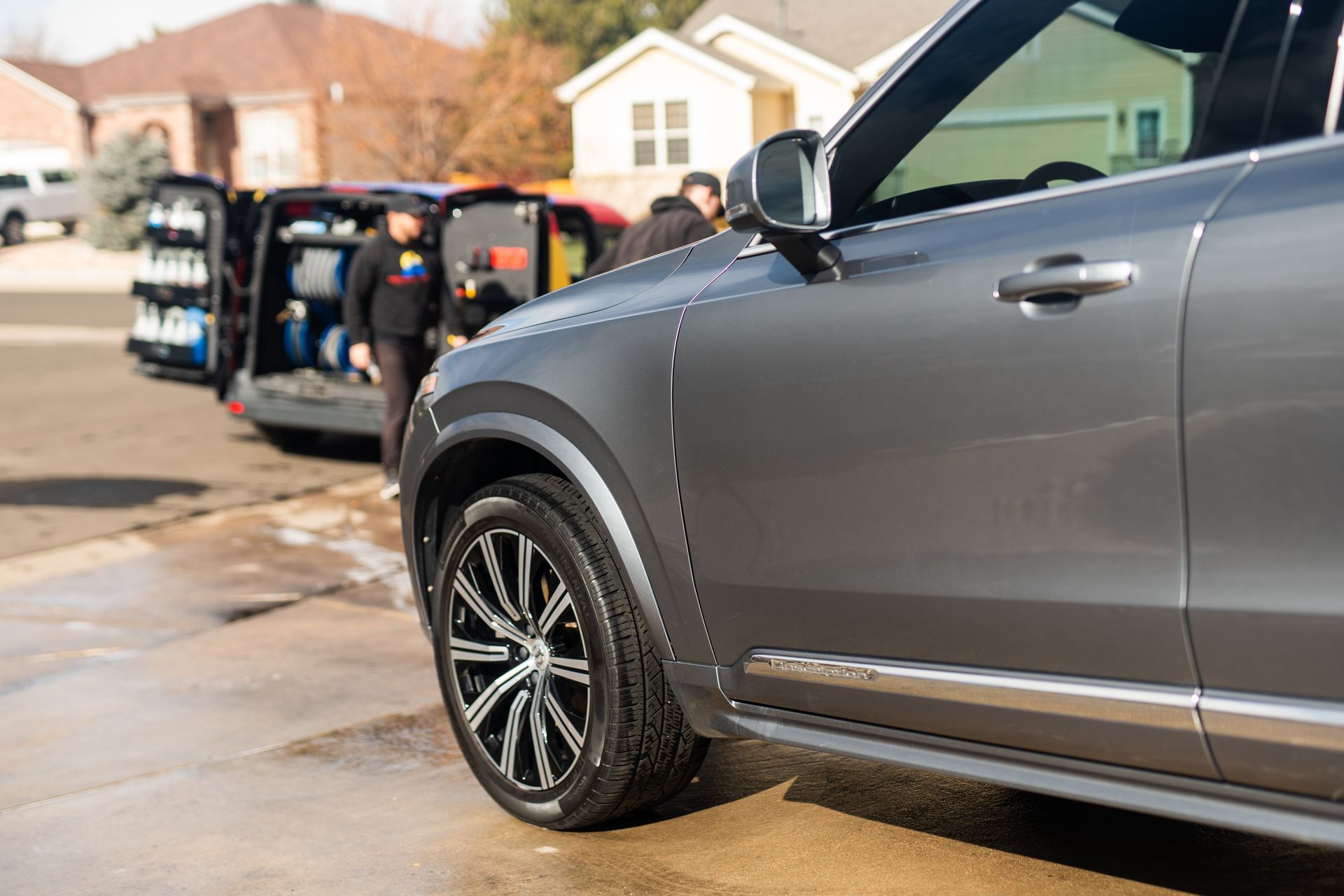 A gray car is parked in a driveway next to a house.