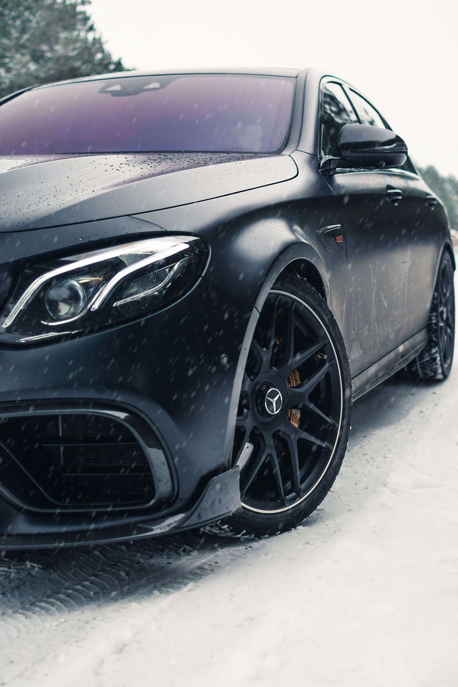 A black car is parked in the snow.