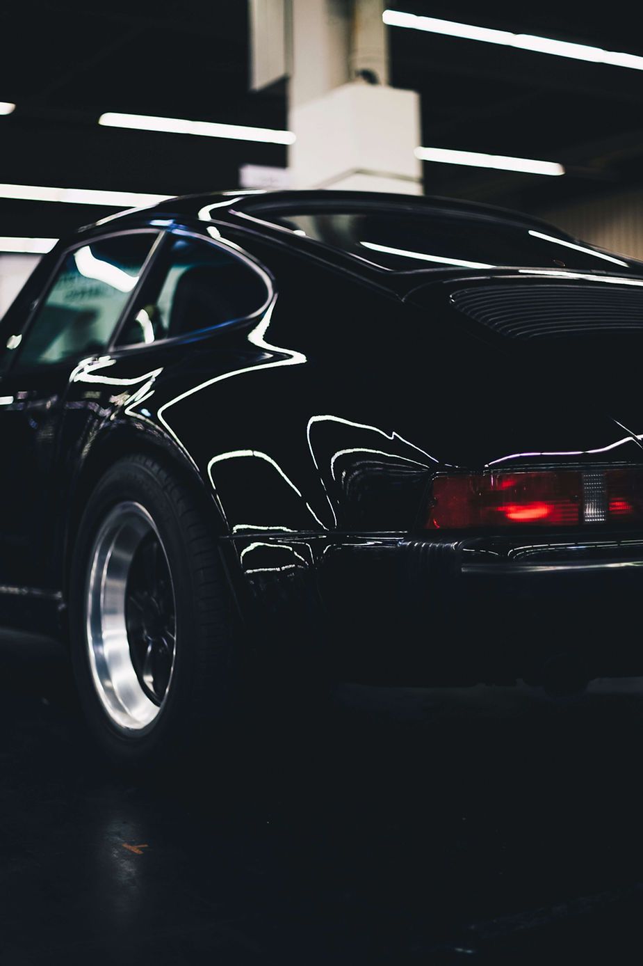 A black car is parked in a dark room.