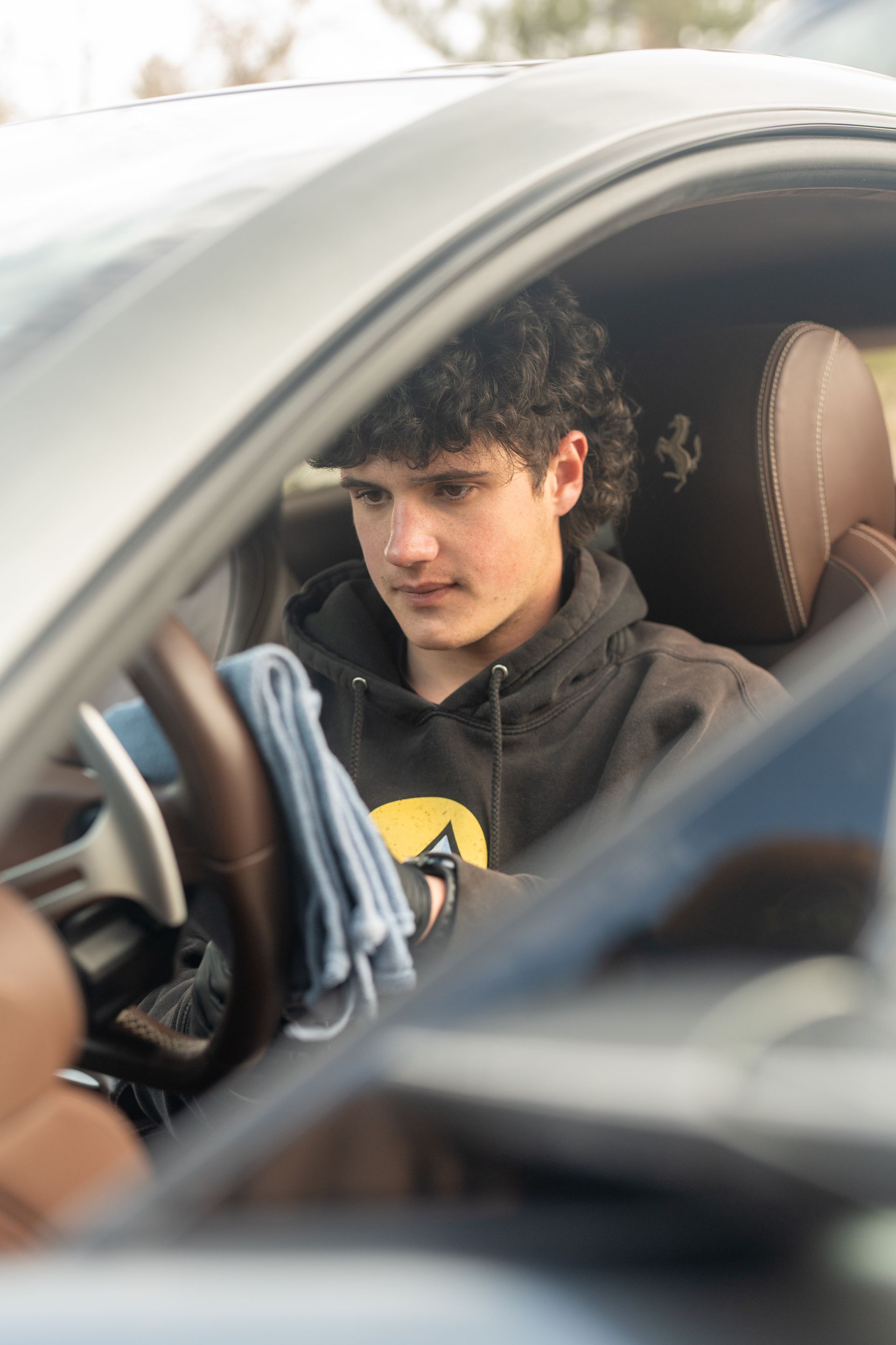 A young man is sitting in the driver 's seat of a car.