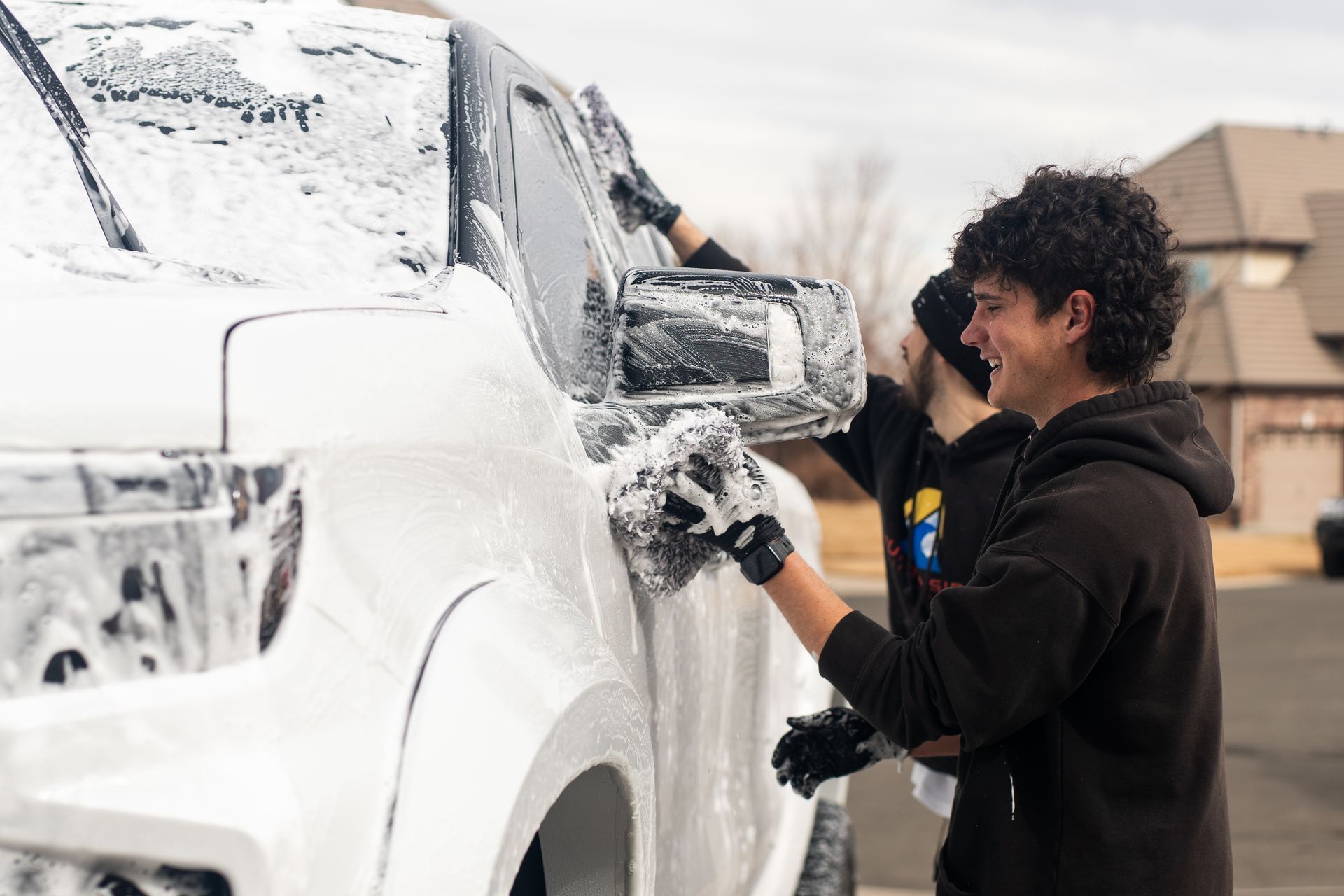 A man is washing a white truck with foam.