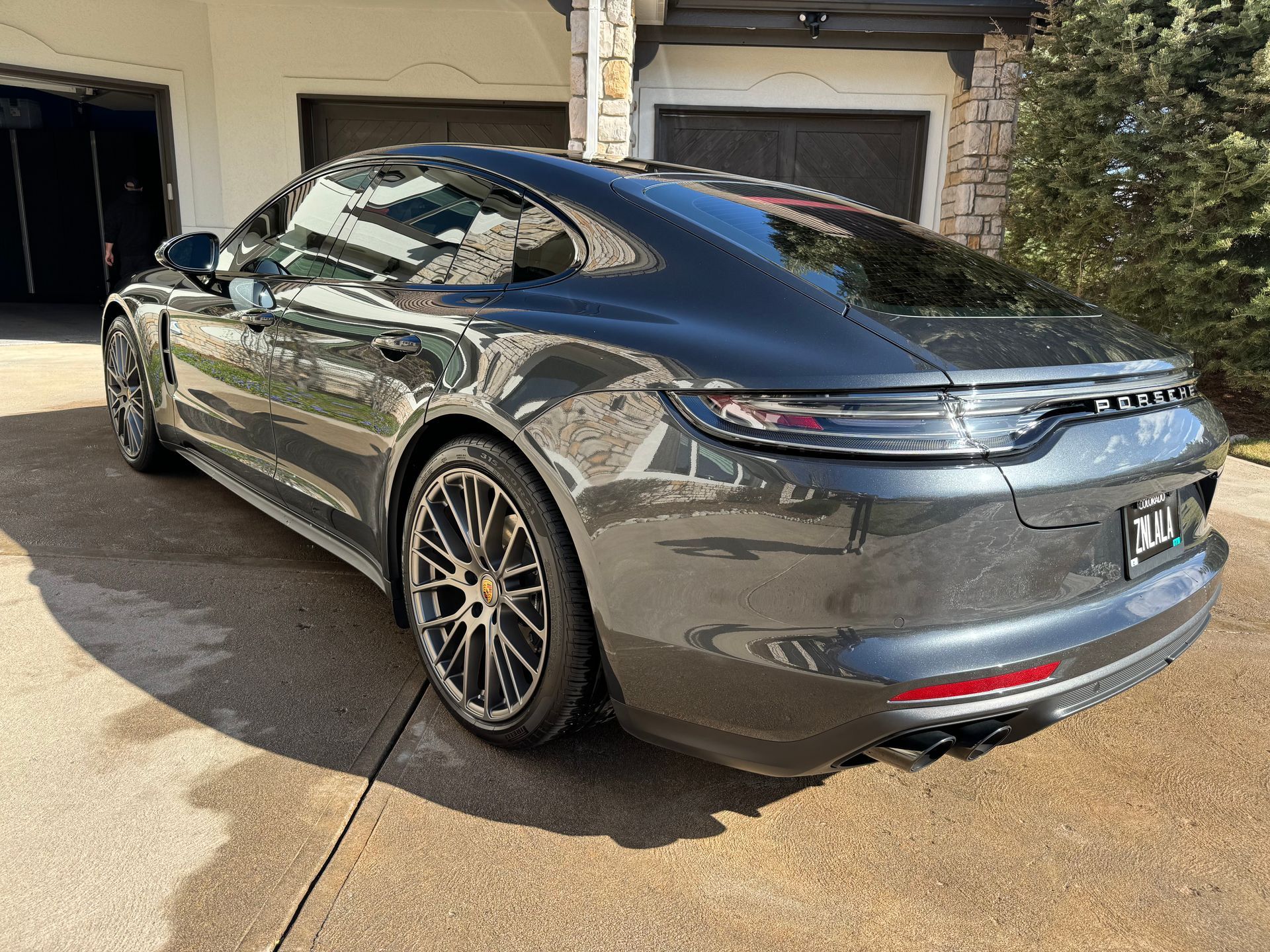 A black porsche panamera is parked in a driveway in front of a garage.