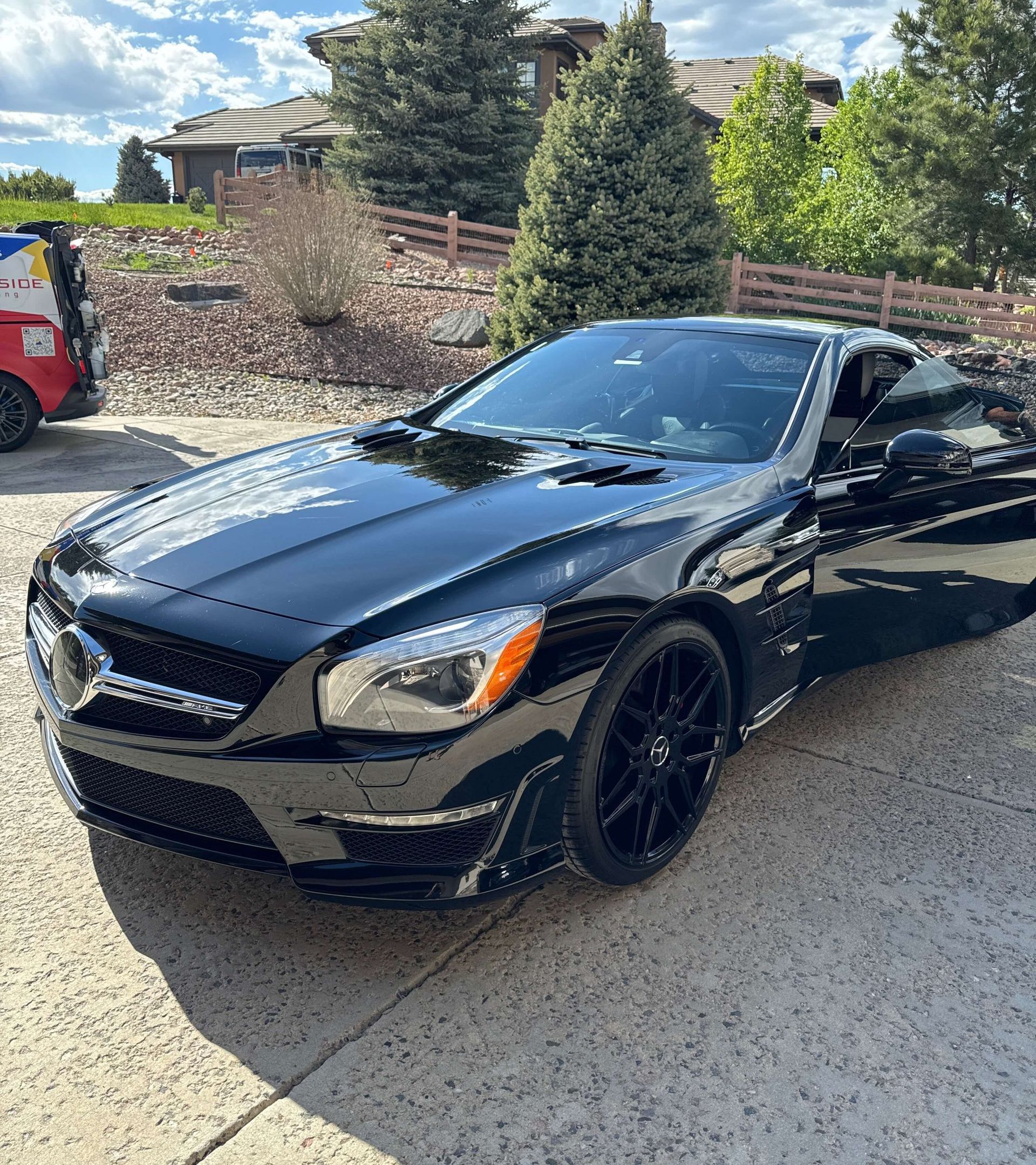 A black sports car is parked in a driveway next to a house.