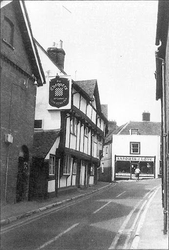 Street scene with The Chequers pub, timber-framed building, and Barber Shop in the distance.
