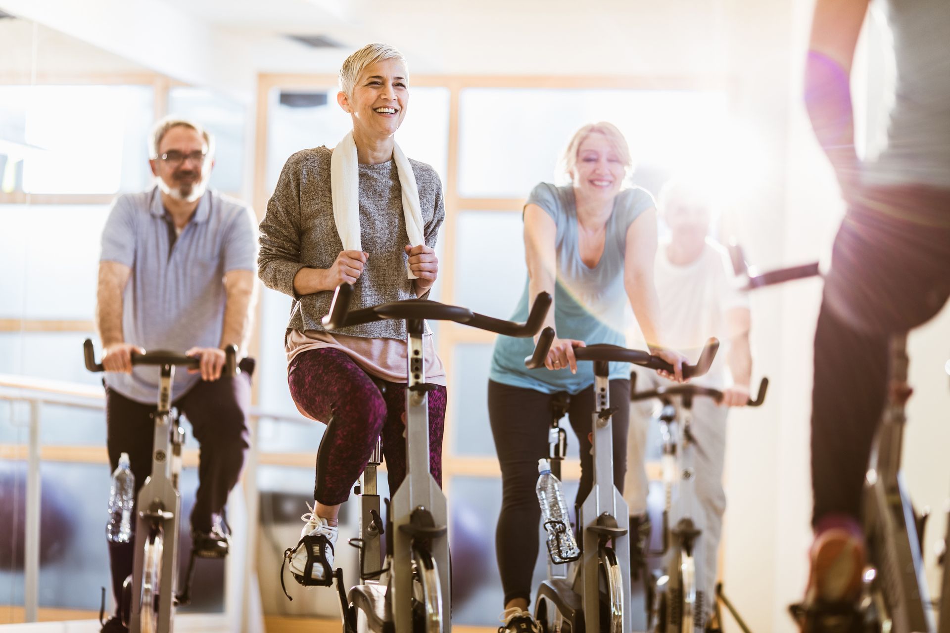 People pedaling stationary bikes in a bright fitness studio