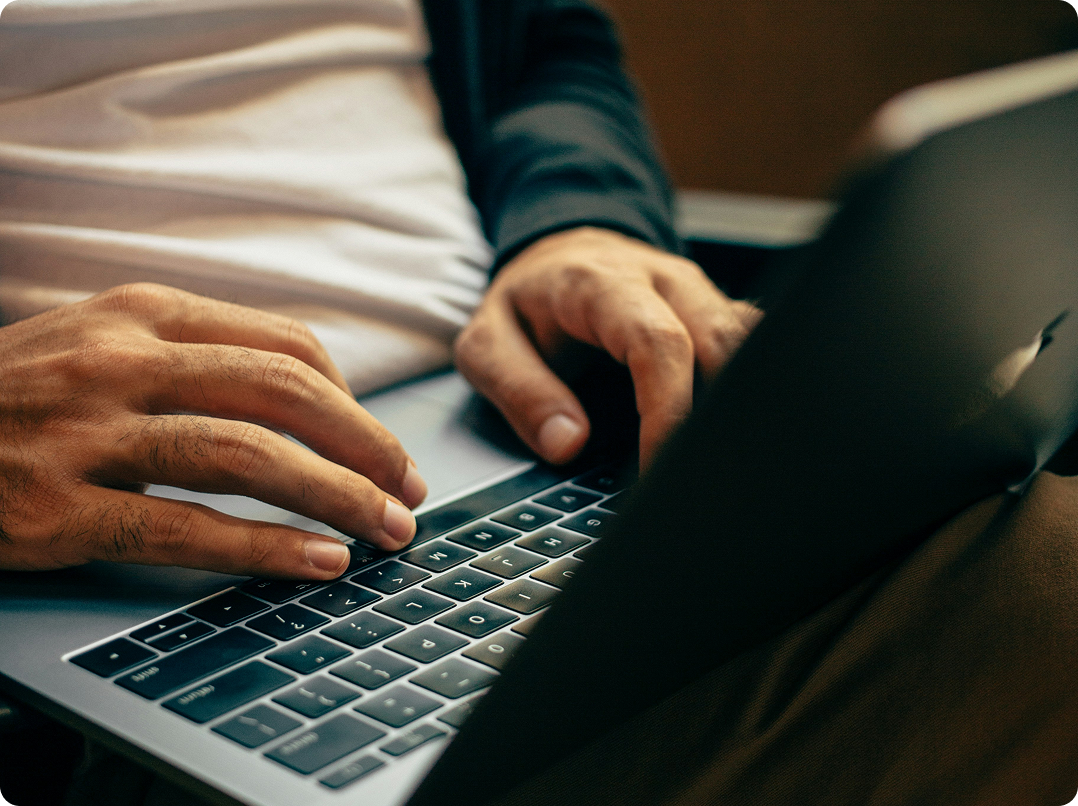 Hands typing on a laptop keyboard in a dimly lit setting