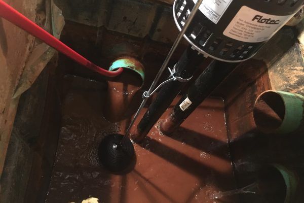 Puisard avec pompe, tuyaux et interrupteur à flotteur. Plomberie rouge et verte, pompe noire et eau.