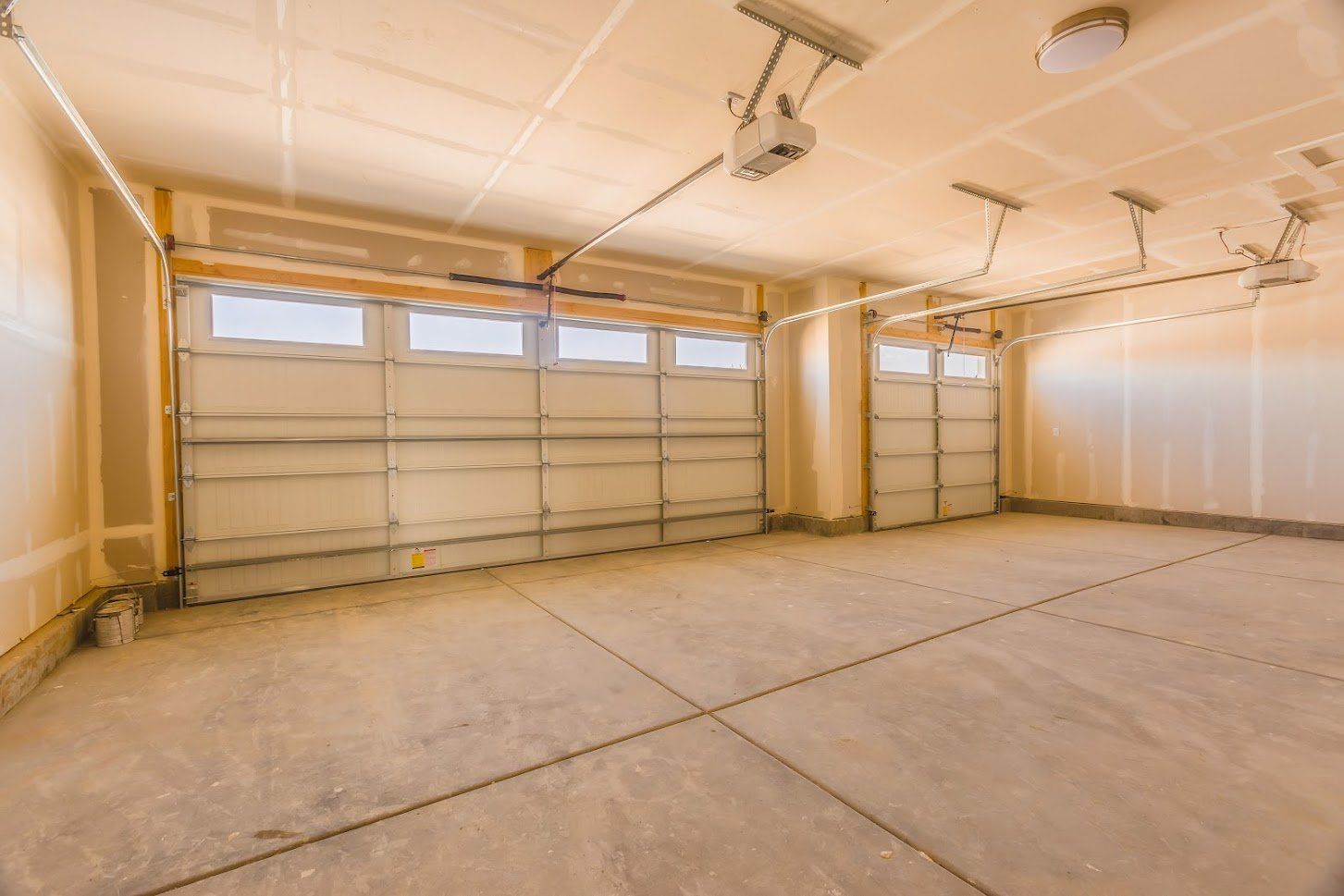 Empty garage with concrete floor and two overhead doors.
