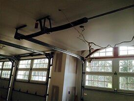 Garage interior with open door, windows, and overhead garage door opener.