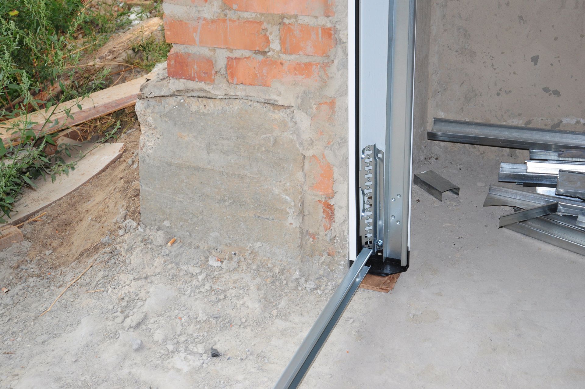 Vertical garage door track mounted beside a brick wall during garage door repair